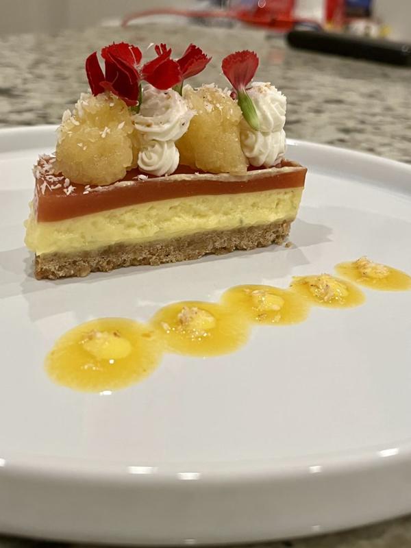 A plated dessert cake with mango sauce dots