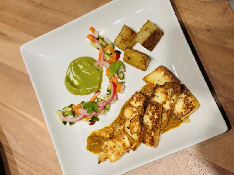 Seared fish plated with a green herb swoosh