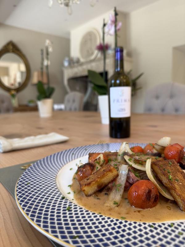 A plated dinner course beside wine